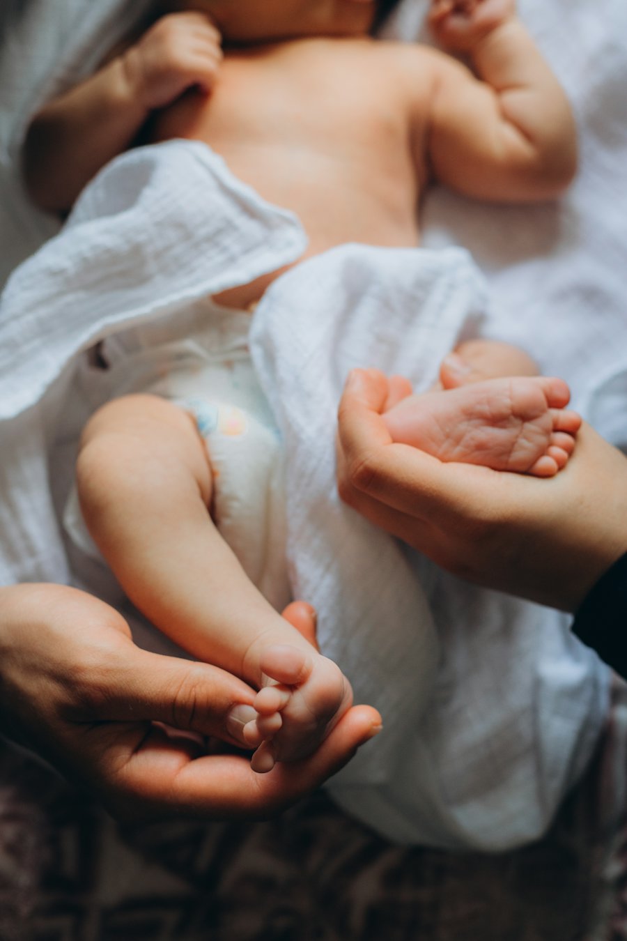 An adult's hands gently holding a sleeping baby's feet